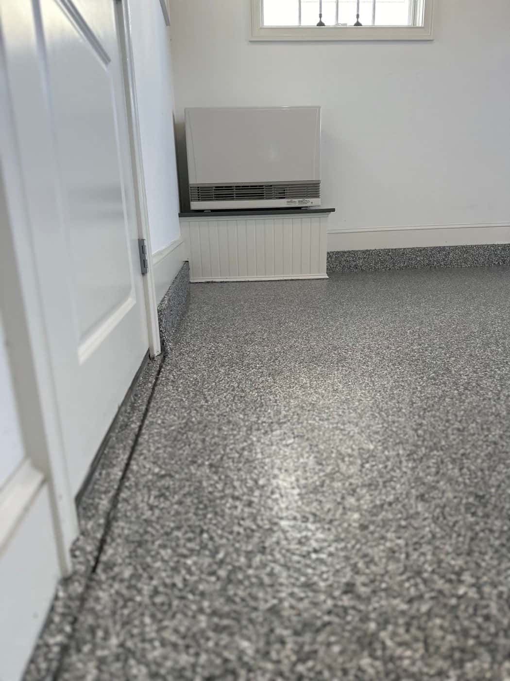 Finished basement with a light flake epoxy floor and white walls