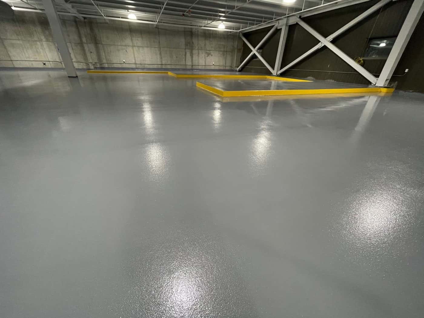 Warehouse floor coated in gray epoxy with yellow safety line striping